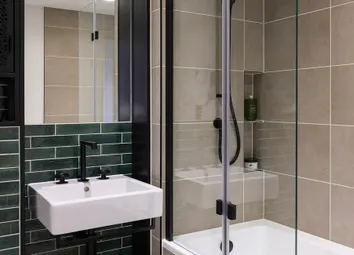 Bathroom With Shower Over Bath, Wash Basin With Mirror, Shelving And Sea-Green Tiling.
