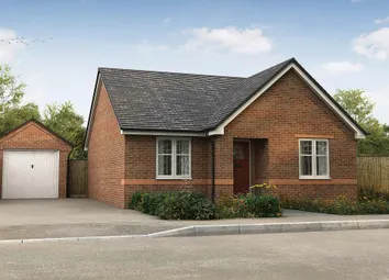 A Brick Bungalow With A Detached Garage Sits On A Paved Driveway In Front Of A Wooded Area Under A c