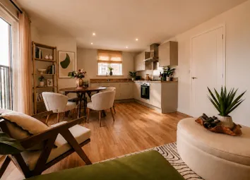 A Modern Living And Dining Area With A Kitchen In The Background Features A Plush Green Ottoman And