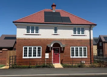A Modern Two-Story House With A Red-Tiled Roof And Solar Panels Sits Behind A Black Metal Fence