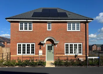 A Two-Story Red Brick House With Solar Panels And A Green Front Door Stands Before A Clear Blue Sky