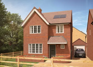 A Two-Story Red Brick House With Solar Panels On Its Roof Stands Behind A Wooden Fence And Small Gar