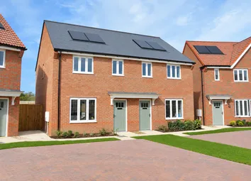 A Red-Brick House With Solar Panels Stands Behind A Paved Driveway And Green Lawns Under A Clear Blu