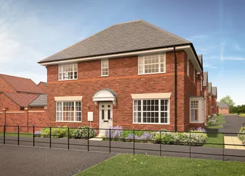 A Red Brick House With A White Door And Large Windows Sits Behind A Low Fence And Flowerbed