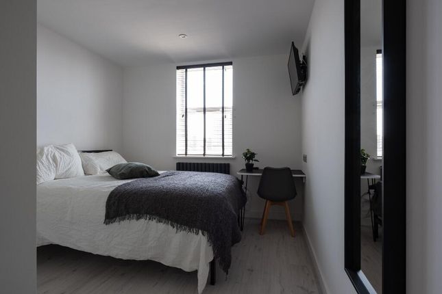 A Spacious And Tidy Bedroom Featuring A Large Bed,...