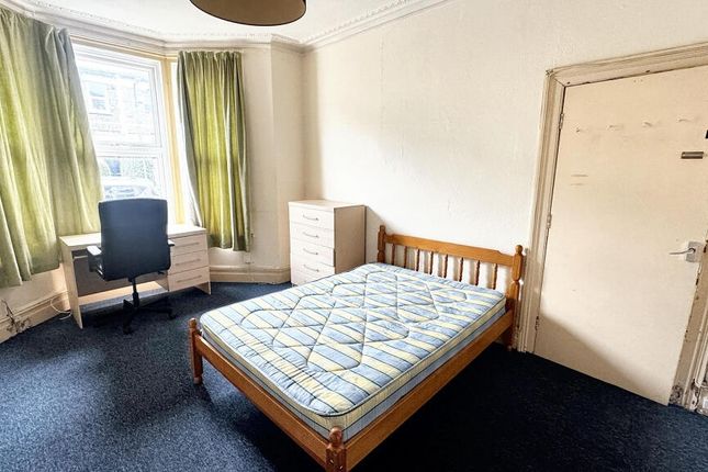 A Modest Single Bedroom With A Wooden Bed Frame, A...
