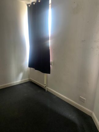 A Small Bedroom With Dark Curtains Partially Cover...