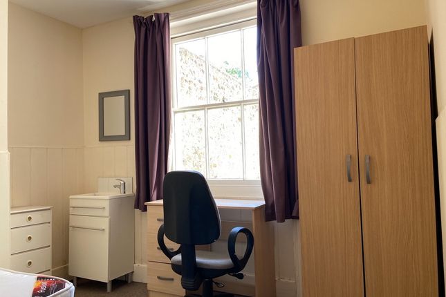 A Bright Single Bedroom Featuring A Window With Pu...