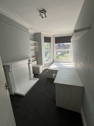 A Cozy Single Bedroom Featuring A Large Window Wit...