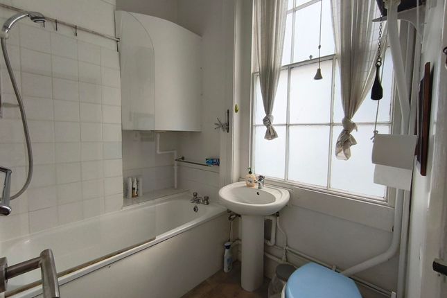 A Compact Bathroom Featuring A Bathtub With A Show...