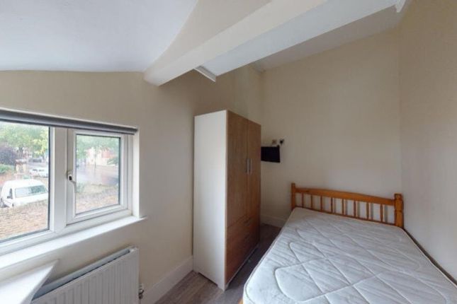 A Cozy Single Bedroom Featuring A Wooden Bed Frame...