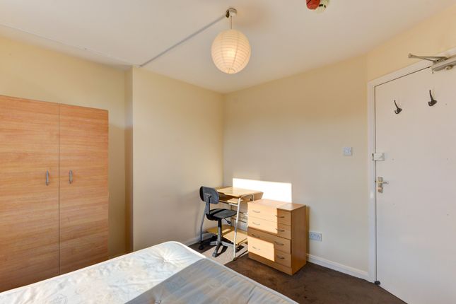 A Well-Lit Bedroom Featuring A Bed, A Wooden Wardr...