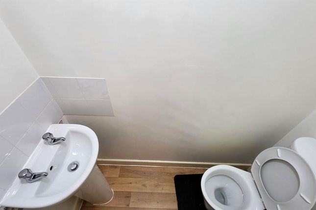 A Clean And Simple Single Toilet With A White Sink...