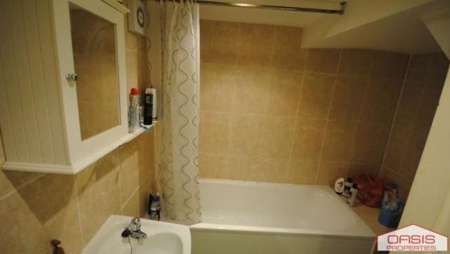 A Clean And Spacious Bathroom Featuring A Bathtub,...