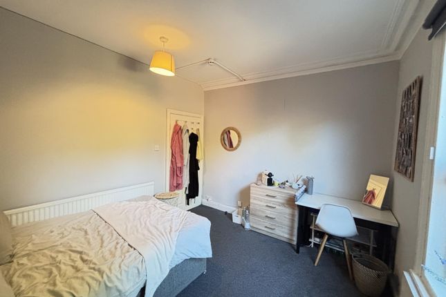 A Bright And Tidy Bedroom With A Neat Bed, A Small...