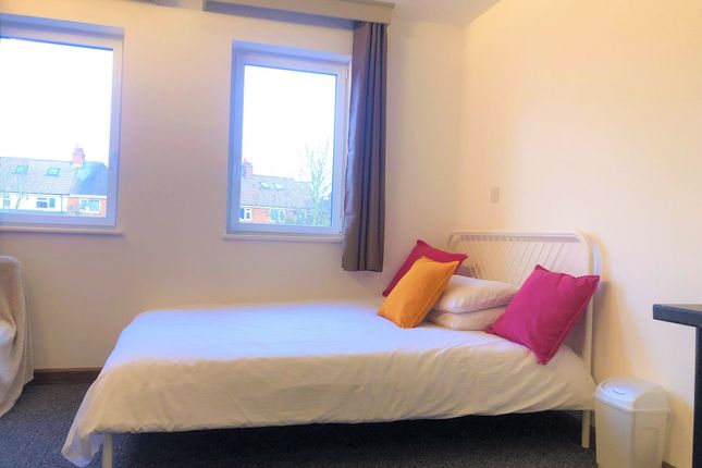 A Cozy Single Bedroom With A Neatly Made Bed Adorn...