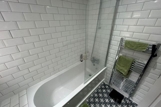 Modern Bathroom Featuring A Clean White Tiled Bath...