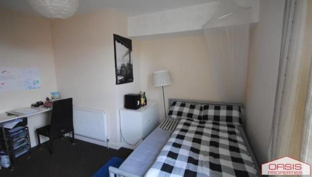 A Cozy Bedroom Featuring A Double Bed With A Check...