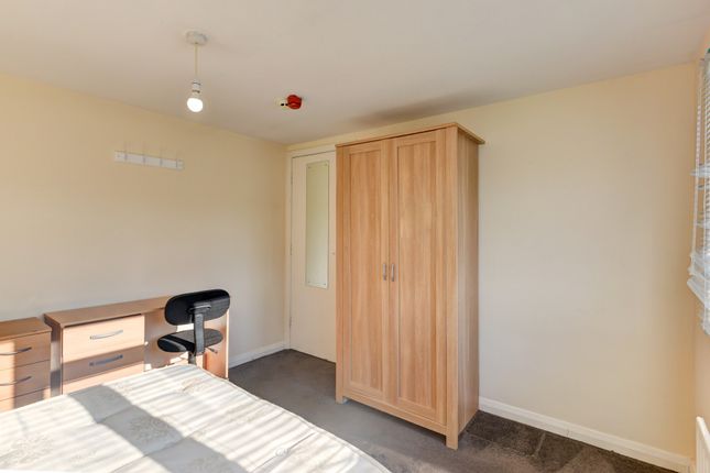 A Neat And Modest Bedroom Featuring A Bed, A Woode...