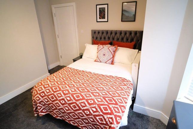 A Cozy Double Bedroom Featuring A Stylish Tufted H...