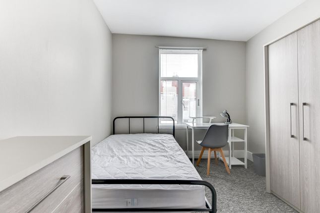 A Tidy And Well-Lit Bedroom Featuring A Simple Bed...