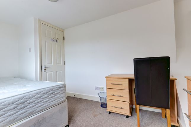 A Simple, Tidy Bedroom Furnished With A Bed, Desk,...