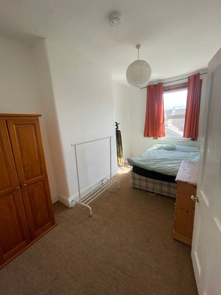 A Cozy Bedroom Featuring A Window With Vibrant Ora...