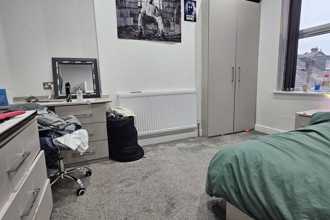 A Cozy Bedroom With A Bed Covered In Green Bedding...