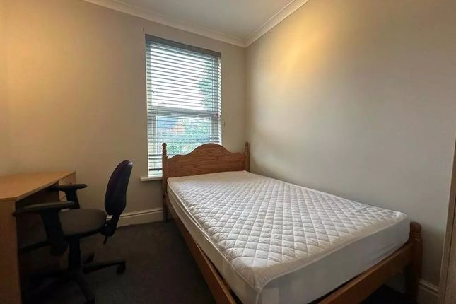 A Cozy Single Bedroom Featuring A Wooden Bed Frame...