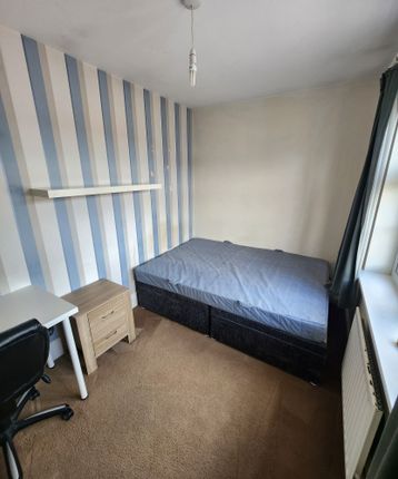 A Cozy Single Bedroom Featuring A Neatly Made Bed,...