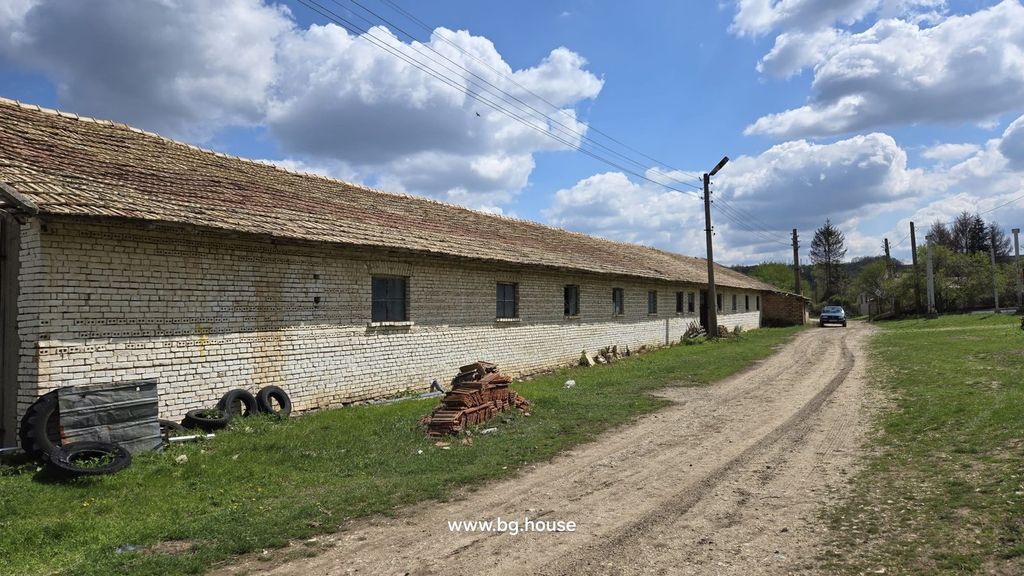 Property photo 1 of 100 Exterior View Of A Long White Brick Farm Building With A Tiled Roof Along A Dirt Road In Osikovo Village