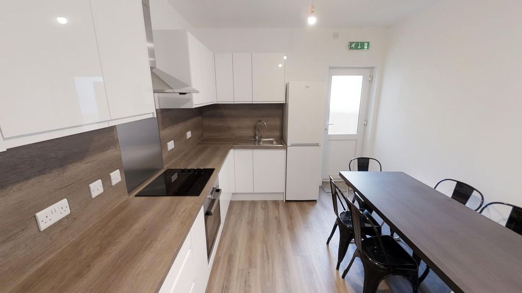 Property photo 3 of 8 A Modern Kitchen With Sleek White Cabinets And Woo...