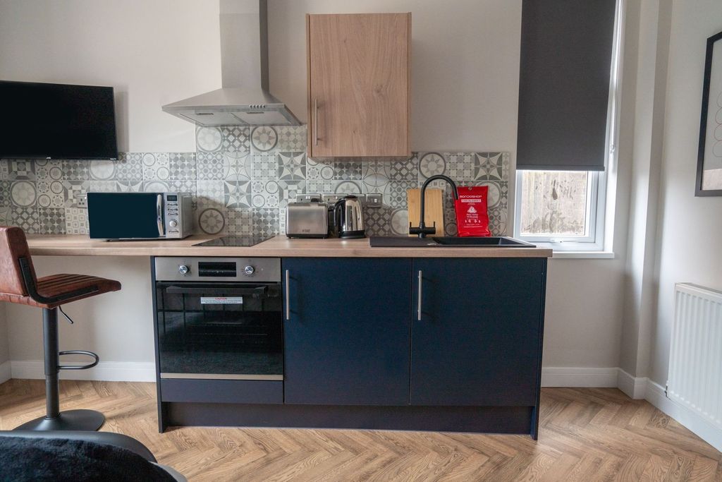 Property photo 3 of 5 Modern Kitchen With Stylish Blue Cabinetry, A Blac...