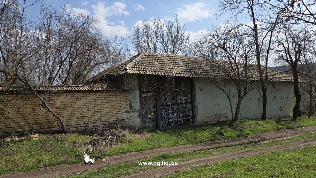 Property photo 3 of 57 Brick Fence With A Large Wooden Gate And A Tiled Roof Structure Behind, Surrounded By Leafless Trees.