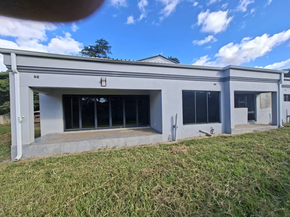 Property photo 2 of 19 Modern Single-Story Building With A Wide Glass Storefront And Concrete Porch, On A Grassy Lot Under A Blue Sky With Clouds.