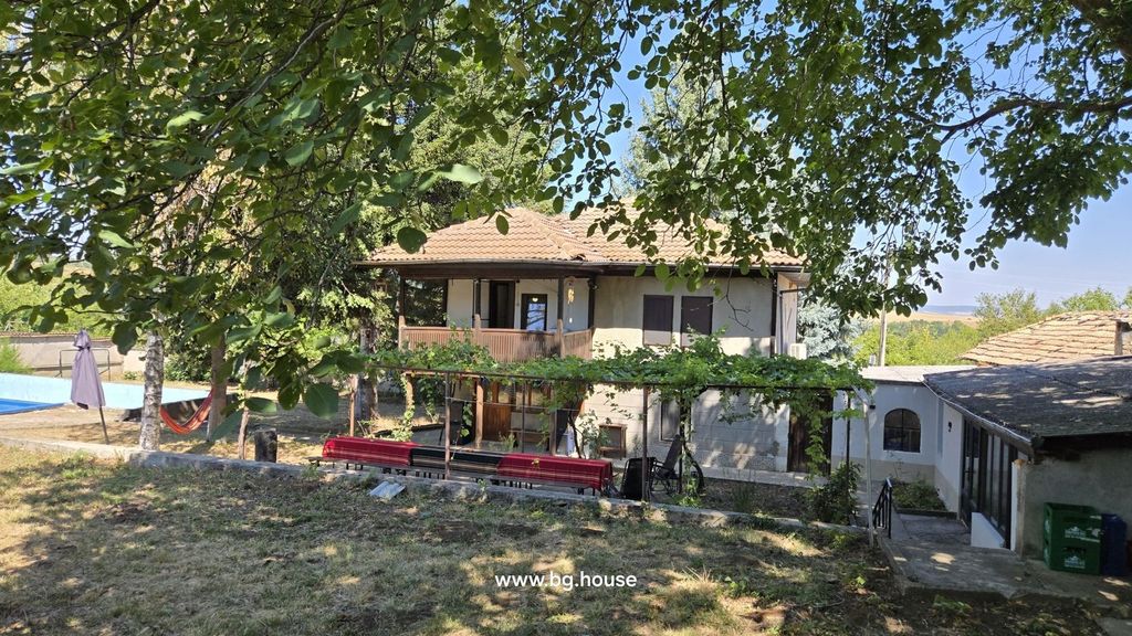 Property photo 1 of 100 View Of A Two-Storey House With A Tiled Roof, Shaded By Trees, Featuring Outdoor Benches With Red Covers And A Hammock In The Garden.