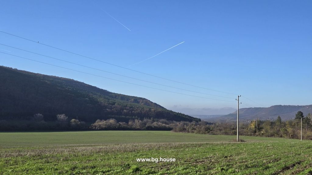 Property photo 2 of 35 Wide Open Green Field Bordered By Wooded Hills Under A Clear Blue Sky With Visible Airplane Contrails.