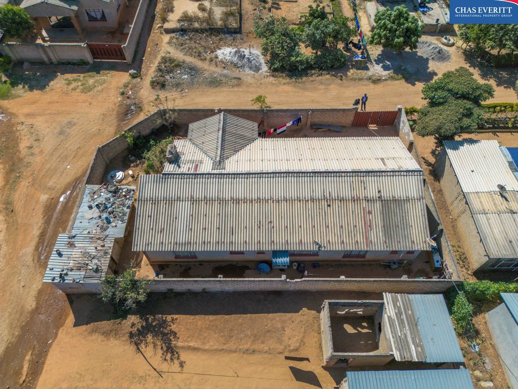 Property photo 2 of 9 Aerial View Of A Dusty Residential Area With Corrugated Metal Roofs, A Walled Yard, And Clothes Hanging On A Line.