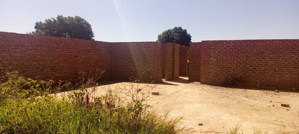 Property photo 2 of 5 Unfinished Brick Building With Interior Walls Forming A Doorway, Dirt Ground, And Sparse Vegetation Under A Bright Sky.