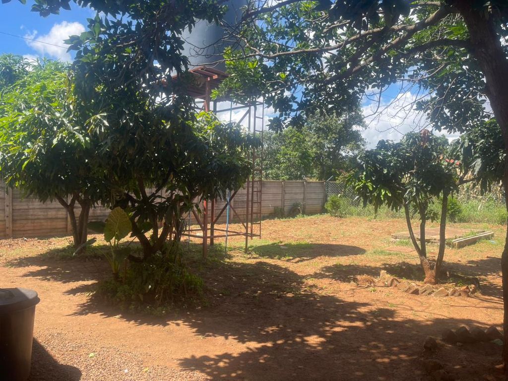 Property photo 2 of 23 Sunny Backyard With Trees, Dirt Ground, And A Metal Play Structure Near A Wooden Fence Under A Blue Sky.