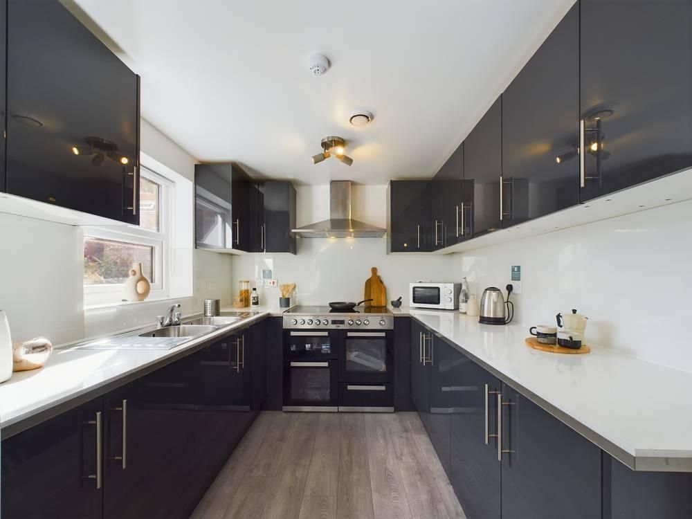 Property photo 3 of 10 Modern Galley-Style Kitchen With Glossy Dark Cabin...