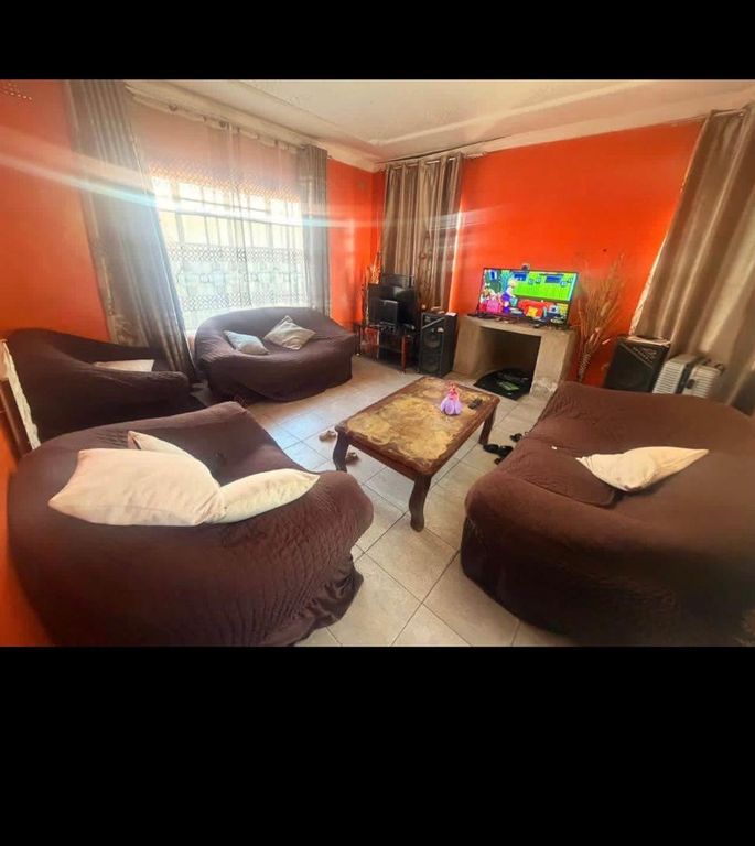 Property photo 1 of 9 Living Room With Orange Walls And Brown Round Couches Surrounding A Wooden Coffee Table, TV And Entertainment Setup Visible.