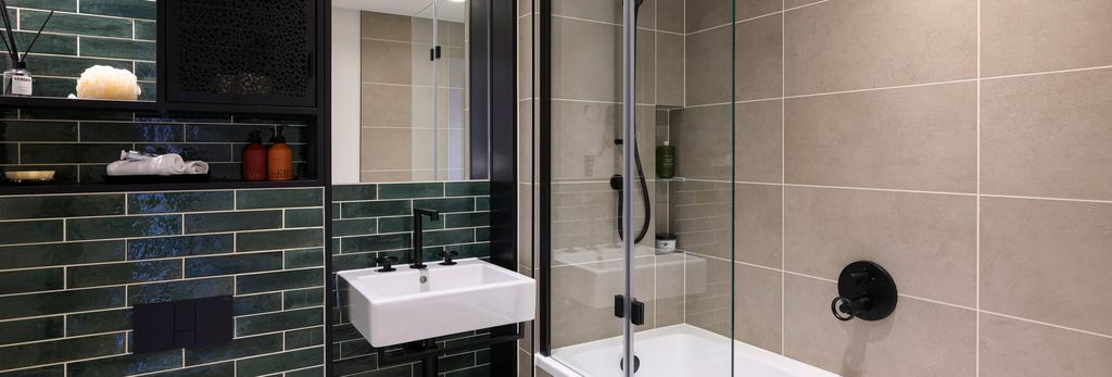 Property photo 1 of 7 Bathroom With Shower Over Bath, Wash Basin With Mirror, Shelving And Sea-Green Tiling.