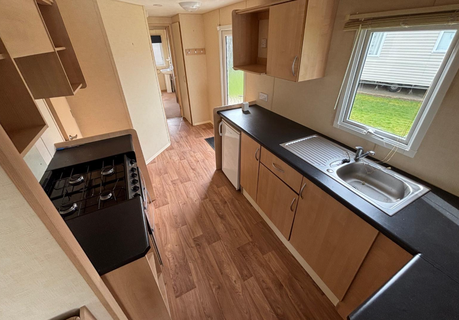 Property photo 2 of 4 Abi Vista Galley Style Kitchen With Wooden Cupboards, Black Worktops And Gas Cooker