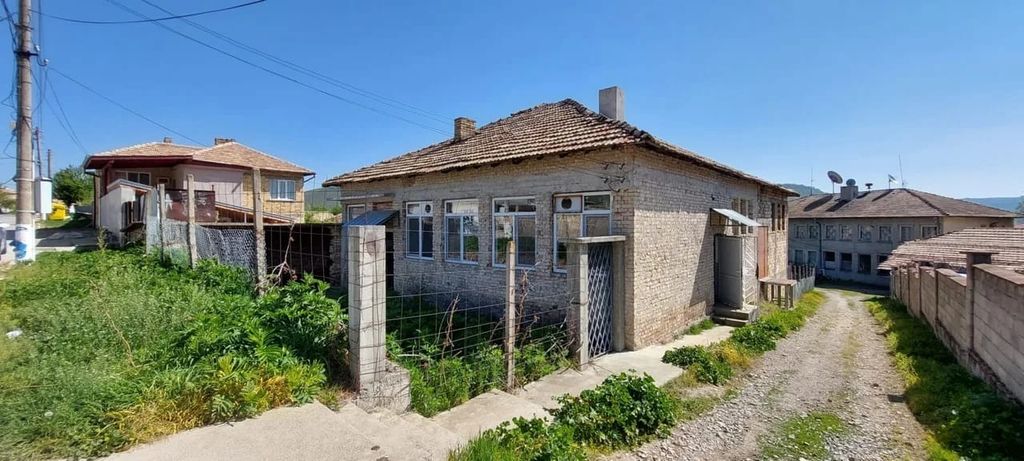 Property photo 1 of 65 Front And Side View Of A Brick House With A Tiled Roof And Fenced Yard On A Sunny Day