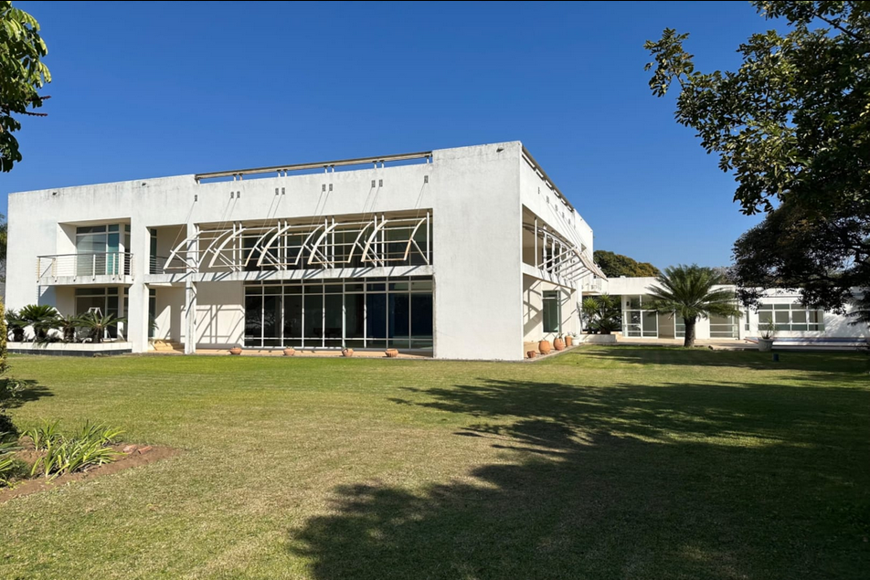 Property photo 1 of 24 Modern White Building With Glass Entrance And Curved Metal Awning On A Sunny Lawn.