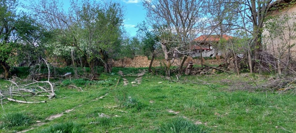 Property photo 2 of 6 Grassy Land Showing Dirt Tracks Leading To A Stone Wall Surrounded By Trees, With Houses Visible Beyond The Wall.