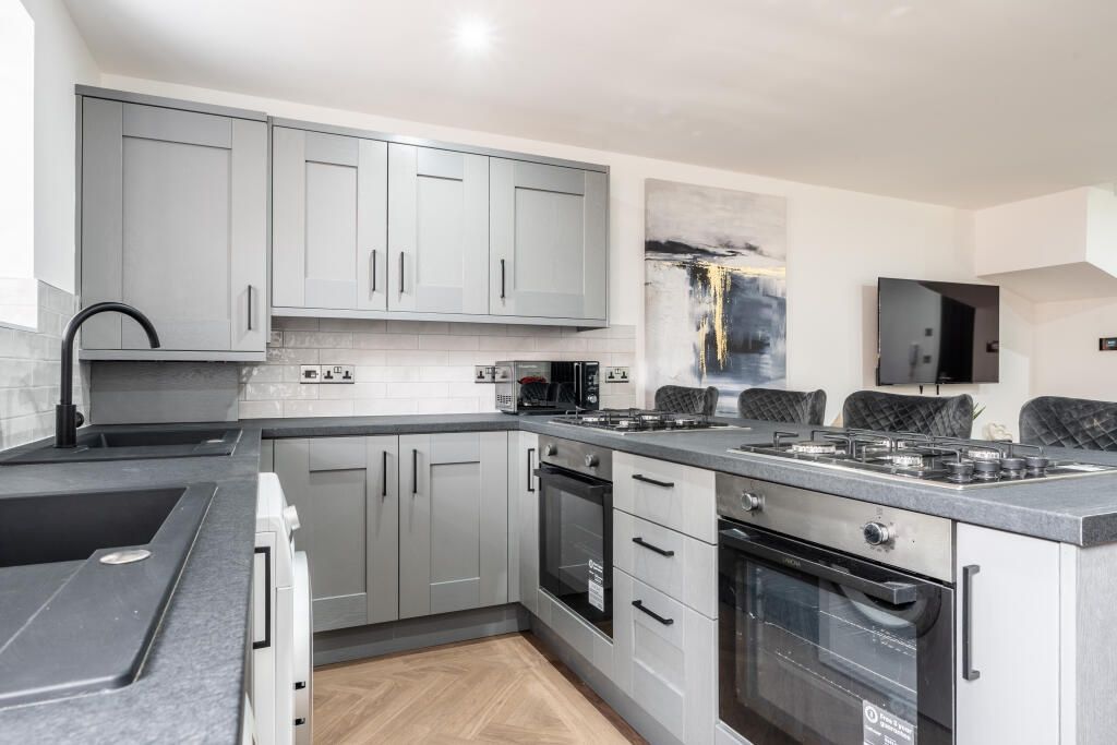 Property photo 2 of 12 A Modern, Well-Lit Kitchen Featuring Sleek Grey Ca...