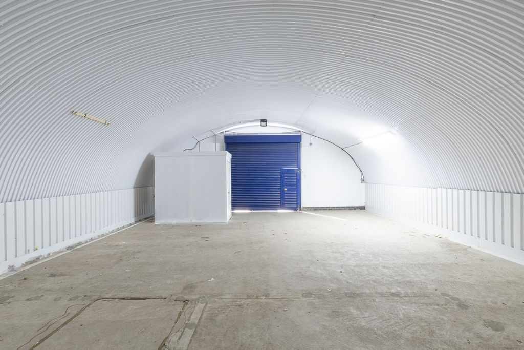 Property photo 3 of 3 An Empty Arch With White Lining, Facing The Front Electric Roller Shutter Entrance, Which Is Closed. There Is A WC Cubicle At The Front Of The Arch.