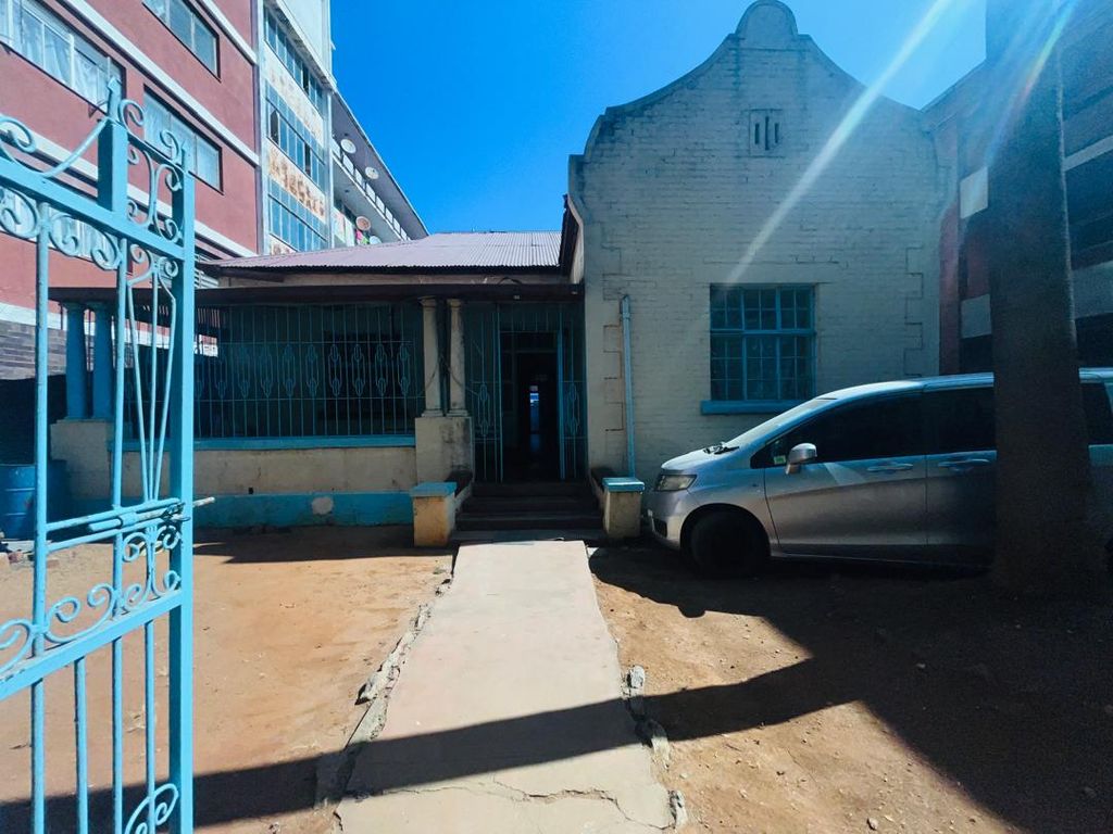 Property photo 2 of 15 Sunlit Courtyard With A Cream Brick House, Blue Window Bars, And A Silver Minivan On The Right; Blue Gate In The Foreground.